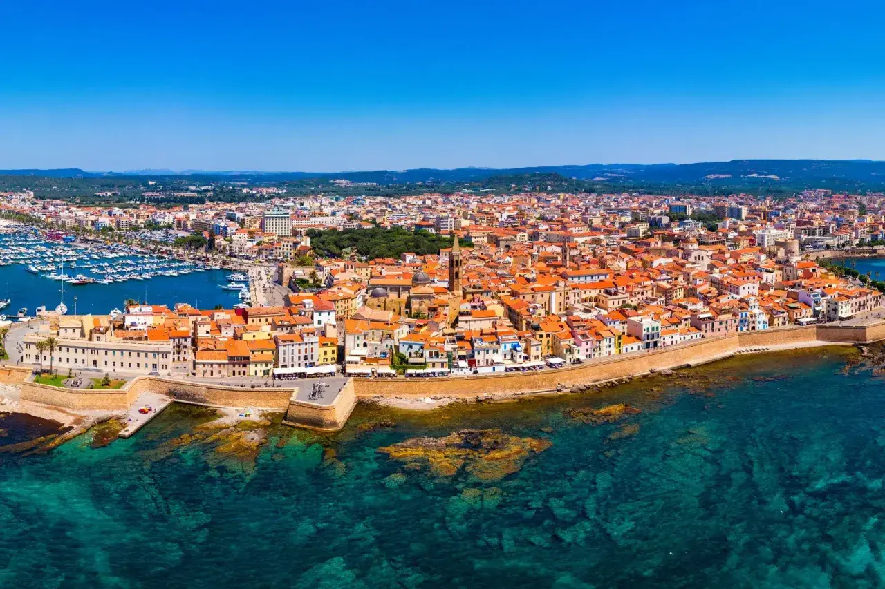 Vista aerea di Alghero, con il porto turistico, le mura storiche e le case dai tetti rossi. Perfetto per scoprire cosa vedere ad Alghero in 3 giorni.