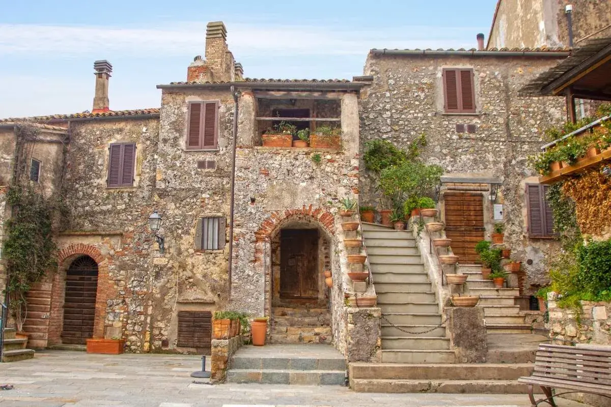Un angolo di uno dei **borghi più belli della Toscana**, con case in pietra, scale in cotto e piante rigogliose.