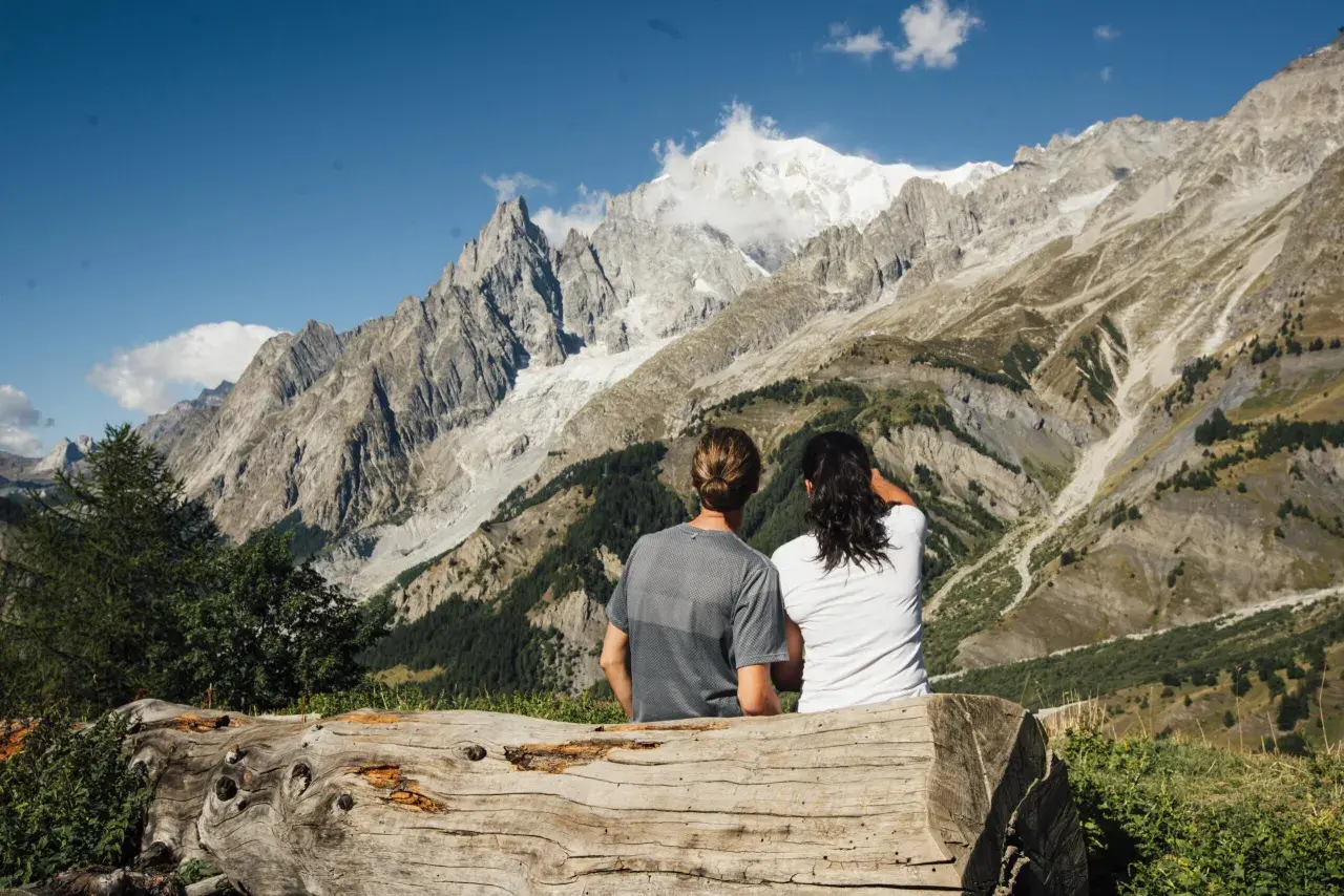 Coppia ammira maestose vette innevate in Val Ferret, godendosi la tranquillità dopo passeggiate facili.