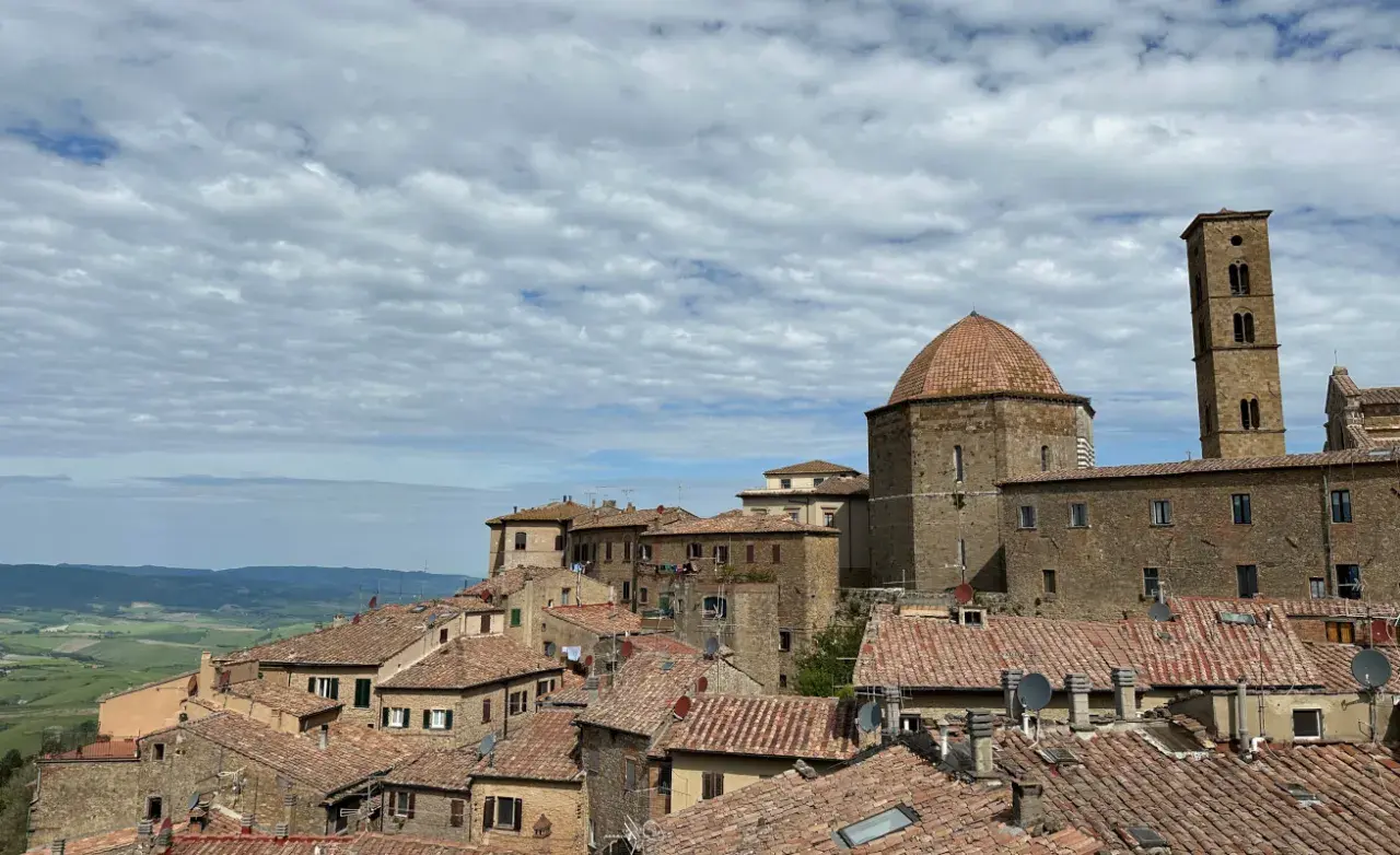 Panoramica di Volterra, con la cupola e il campanile che si stagliano sui tetti rossi. Un paesaggio toscano che ricorda San Gimignano.
