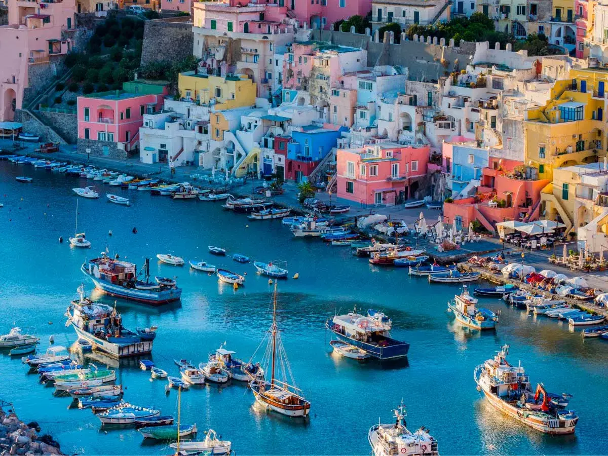 Colorate case a picco sul mare blu, con barche ormeggiate. Un luogo perfetto per escursioni da Napoli.