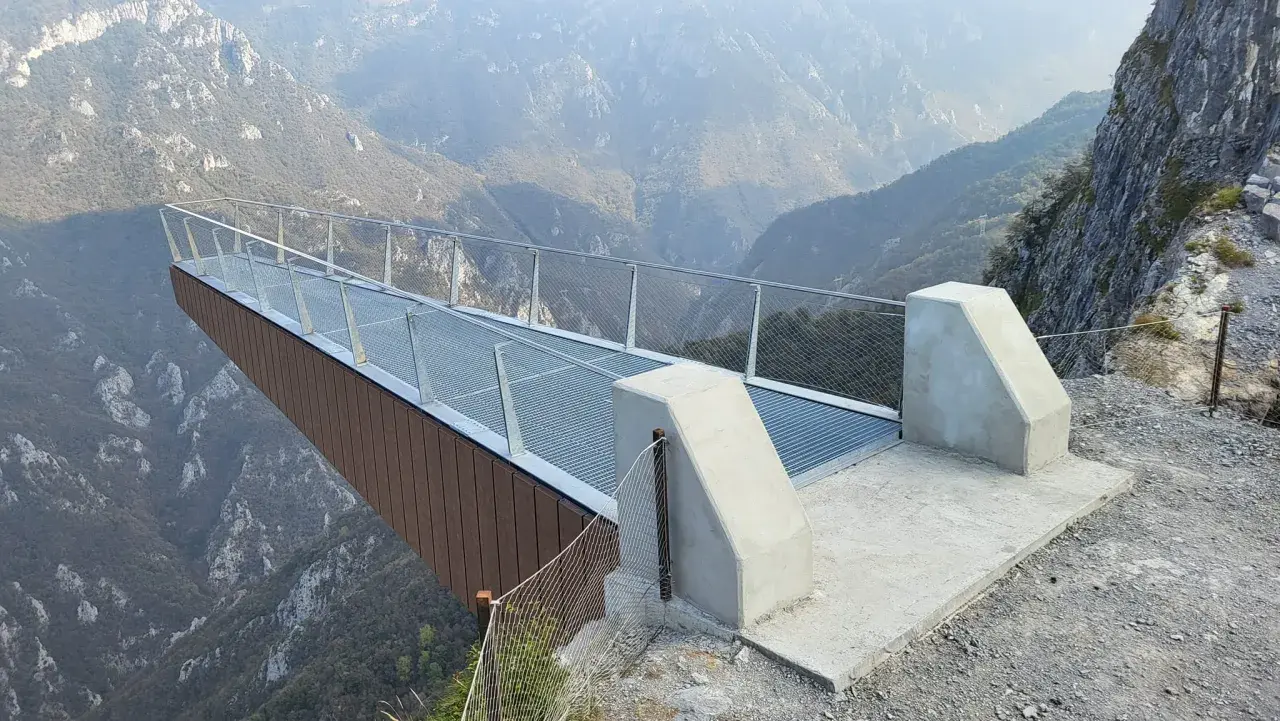 La passerella panoramica "Becco di Dossena" si protende su un profondo canyon, offrendo una vista mozzafiato sulle montagne circostanti.