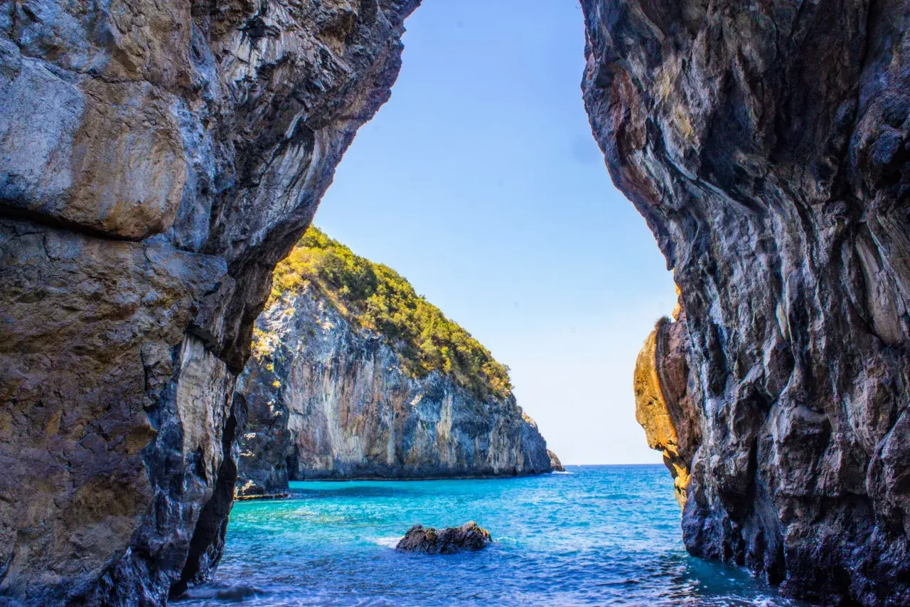 Vista da una grotta su un mare cristallino e una scogliera verdeggiante. Un vero paradiso, tra le scalea spiagge più belle.