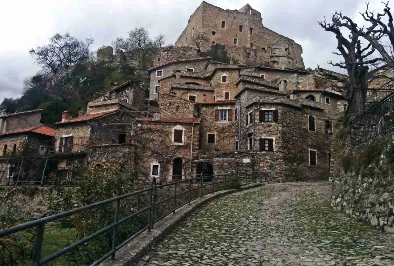 Antico borgo di Castelvecchio di Rocca Barbena, con case in pietra e un castello in cima alla collina.