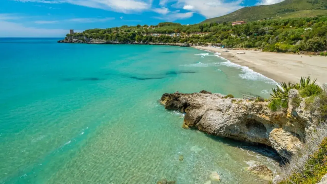 Spiaggia dorata e mare cristallino nel Cilento, uno dei posti più belli del Cilento mare, con una torre antica a picco sul blu.