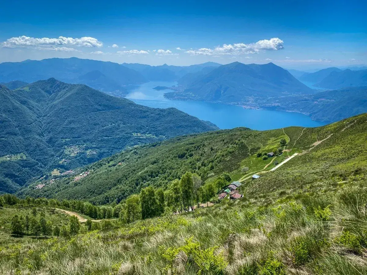 Panoramica mozzafiato di un lago alpino e montagne verdi, ideale per passeggiate vicino Milano.