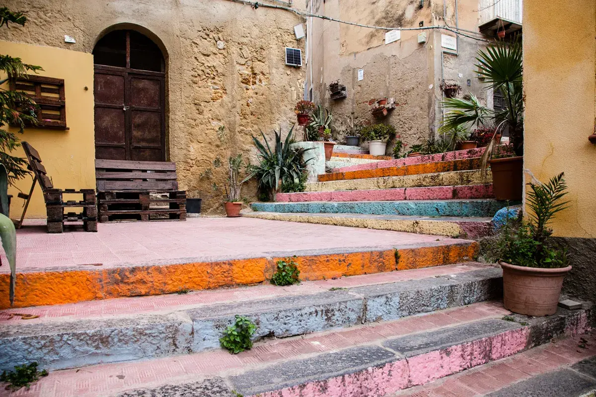 Scalinata colorata, un angolo pittoresco tra le cose da vedere ad Agrigento, con piante e arredi in pallet.