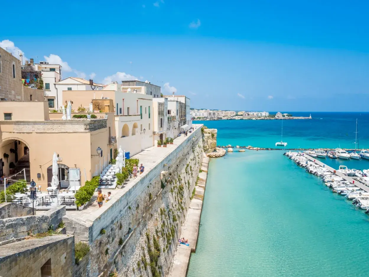 Otranto cosa vedere: un borgo bianco affacciato sul mare turchese, con un porto pieno di barche e un lungomare da sogno.