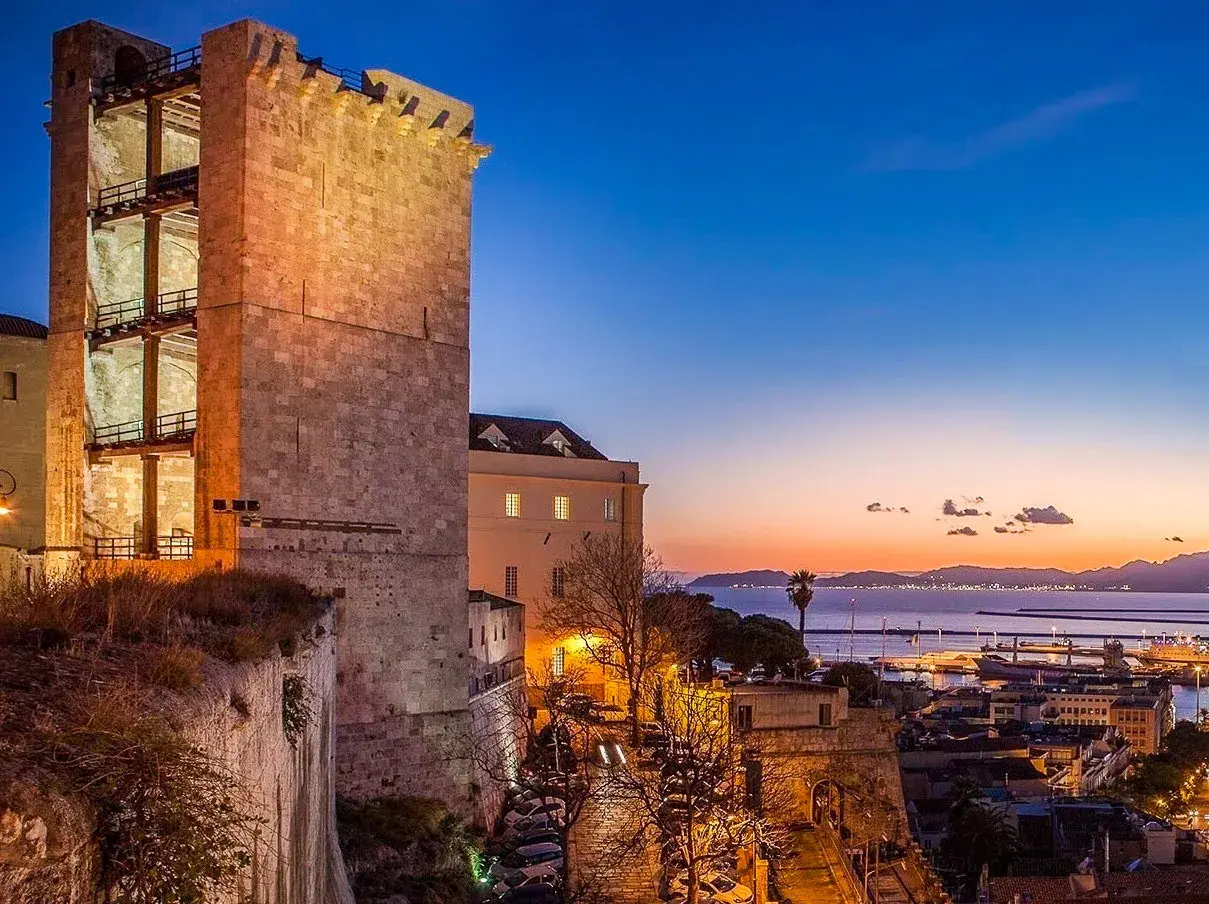 Torre medievale illuminata al tramonto, con vista sul porto e sul mare. Perfetto per scoprire cosa vedere a Cagliari in 3 giorni.