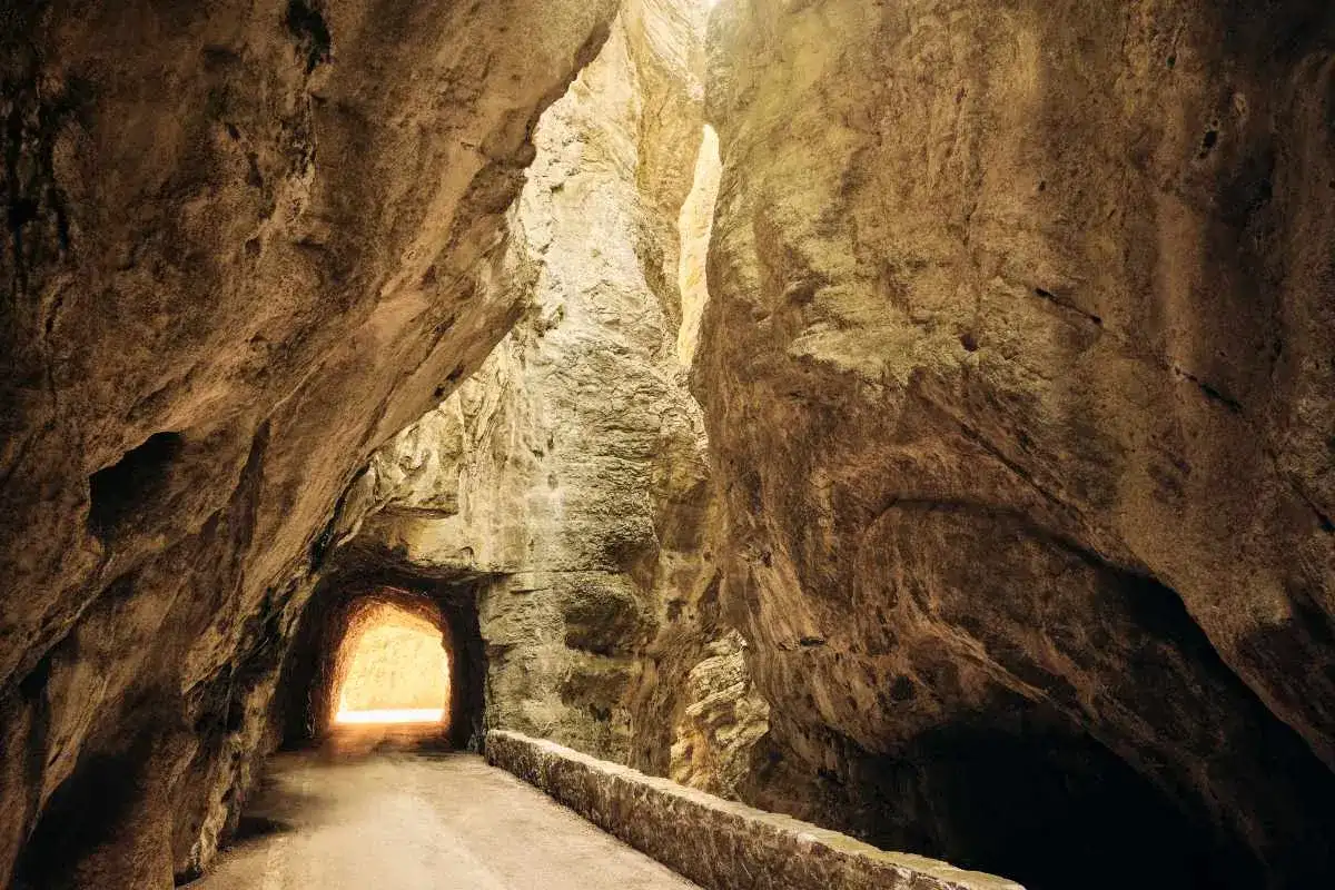 La strada della forra, un sentiero scavato nella roccia, si apre verso una luce intensa.