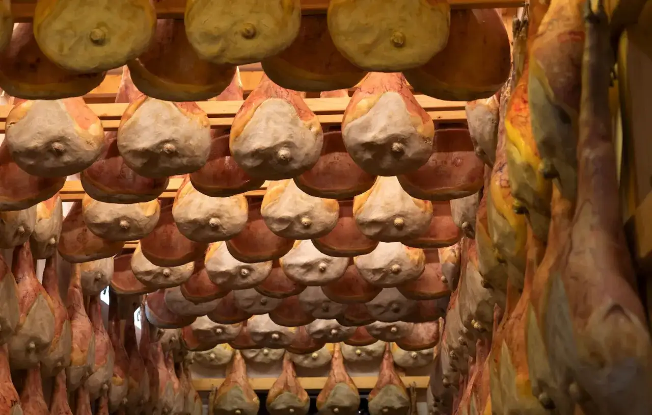 Prosciutti appesi in un locale di stagionatura, un'immagine che evoca i sapori autentici di San Daniele del Friuli.
