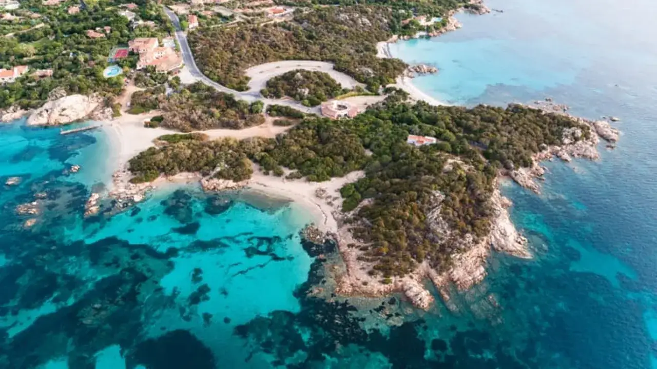 Vista aerea di calette con acque cristalline e vegetazione lussureggiante, tra le migliori spiagge della Costa Smeralda.
