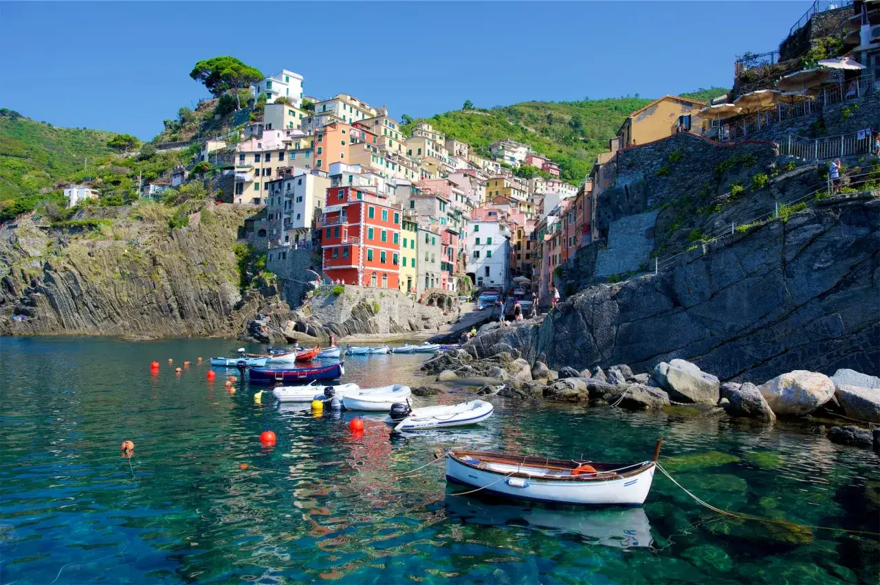 Riomaggiore cosa vedere: case colorate aggrappate alla roccia, barche nel mare cristallino. Un incanto ligure.