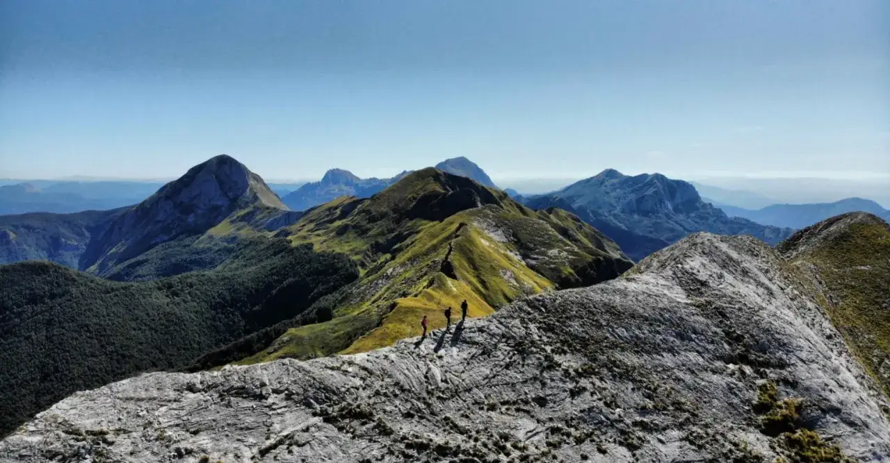 Trekking in Garfagnana, dove si trova questo panorama mozzafiato con vette verdi e rocciose sotto un cielo azzurro.
