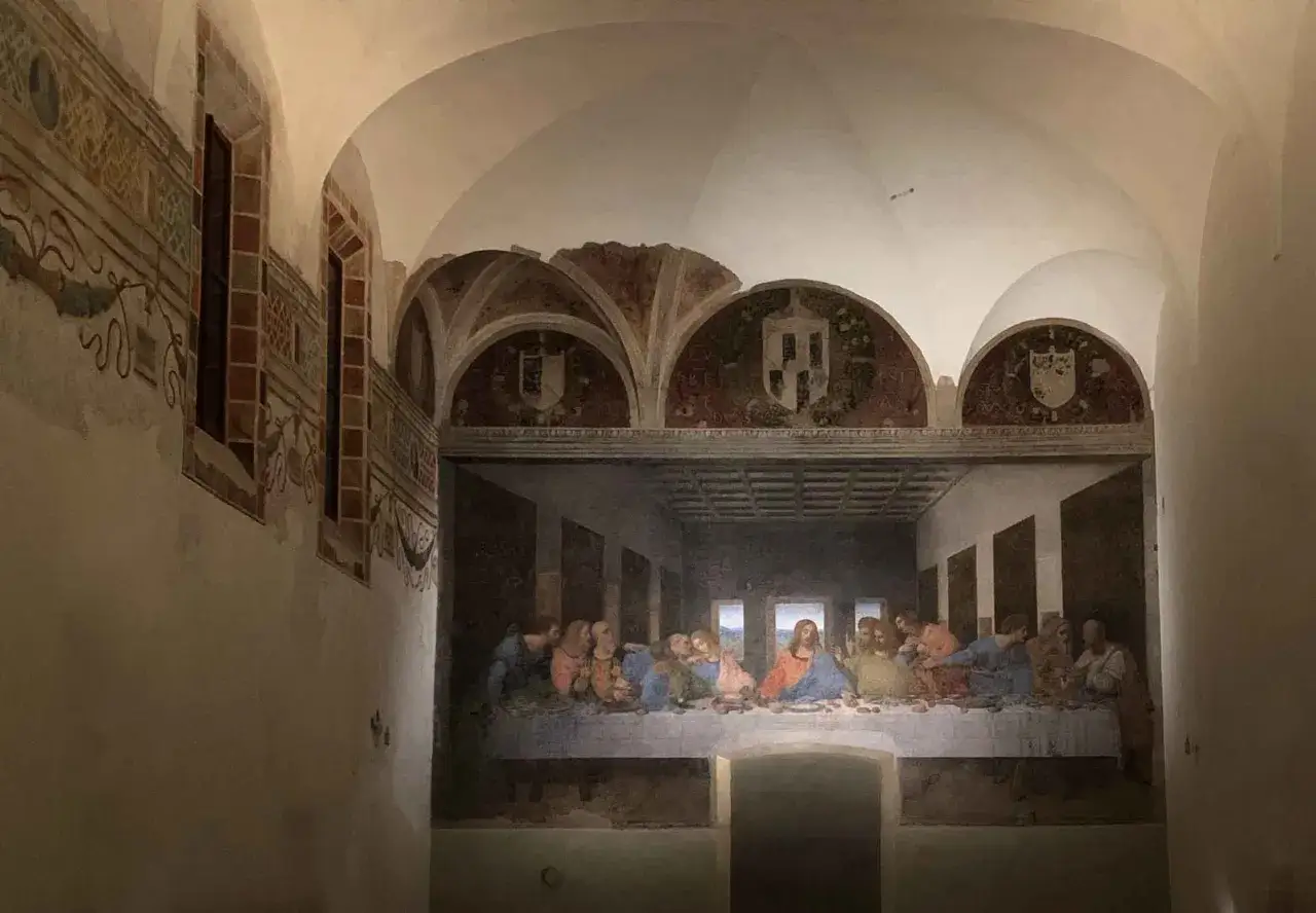 Il cenacolo di Leonardo da Vinci, con i suoi apostoli riuniti attorno a Gesù, in un'ambientazione storica con affreschi sulle pareti.