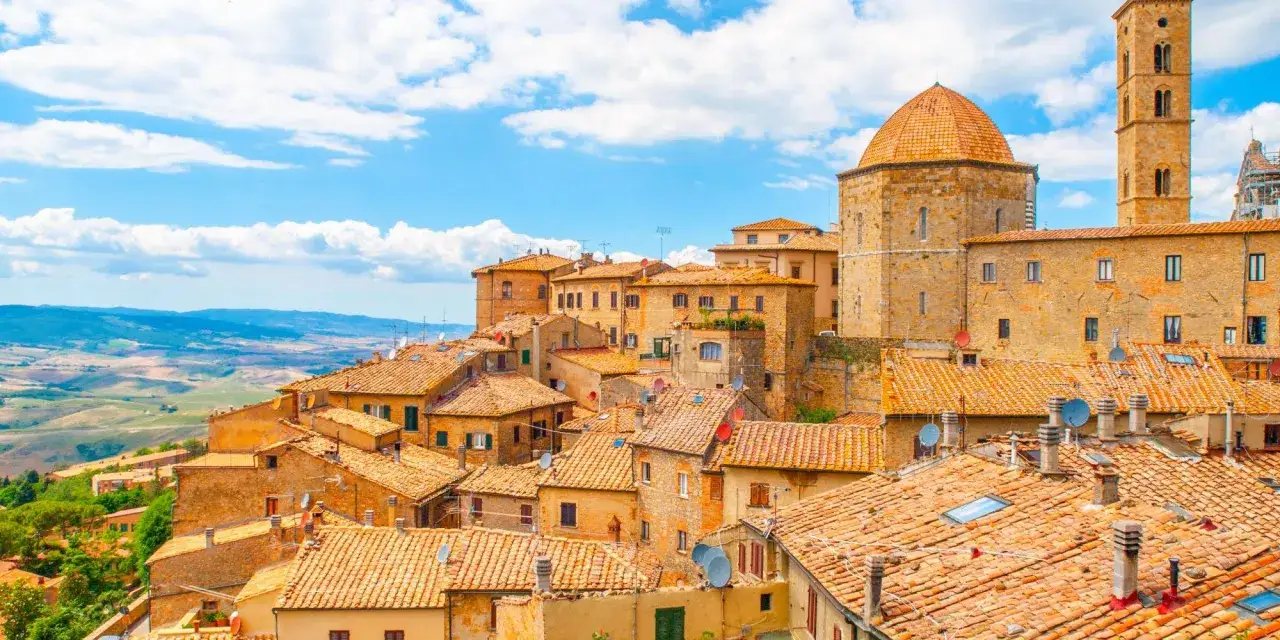 Panoramica di Volterra, con le sue case in pietra e tetti in cotto, che si estende verso le colline toscane, ricordando la bellezza di San Gimignano.