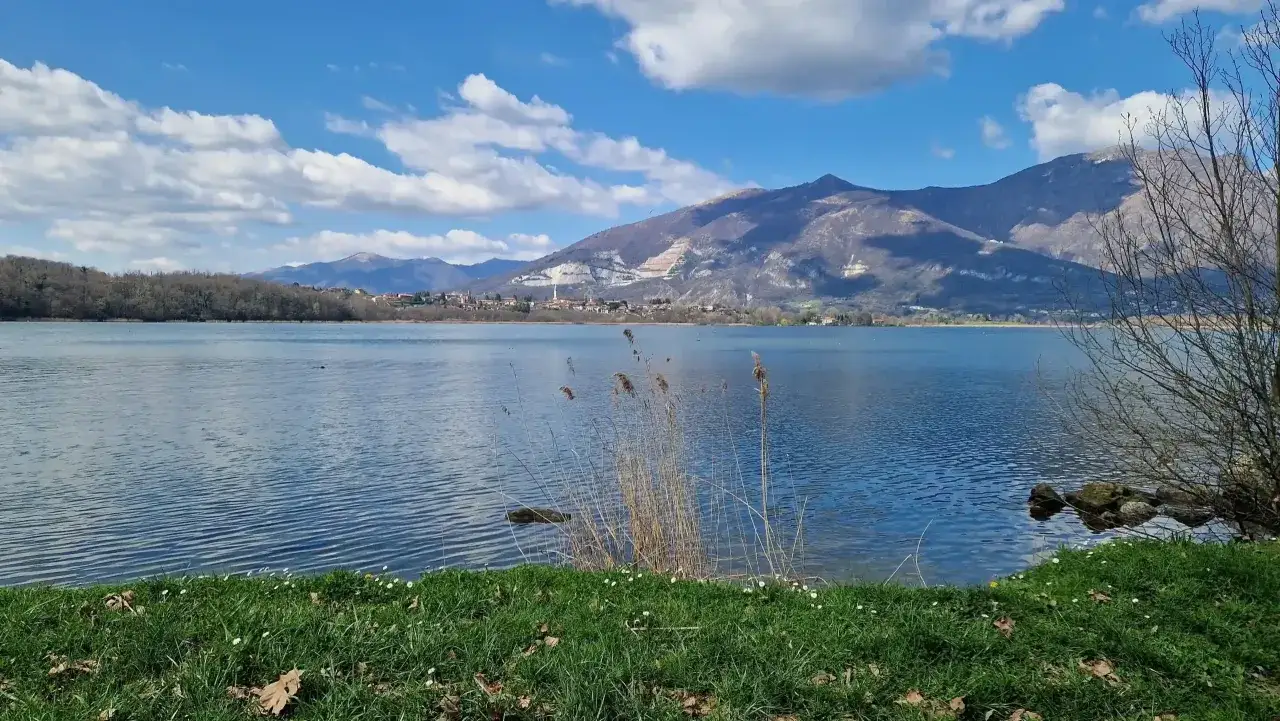 Lago tranquillo con montagne sullo sfondo, ideale per passeggiate vicino Milano.