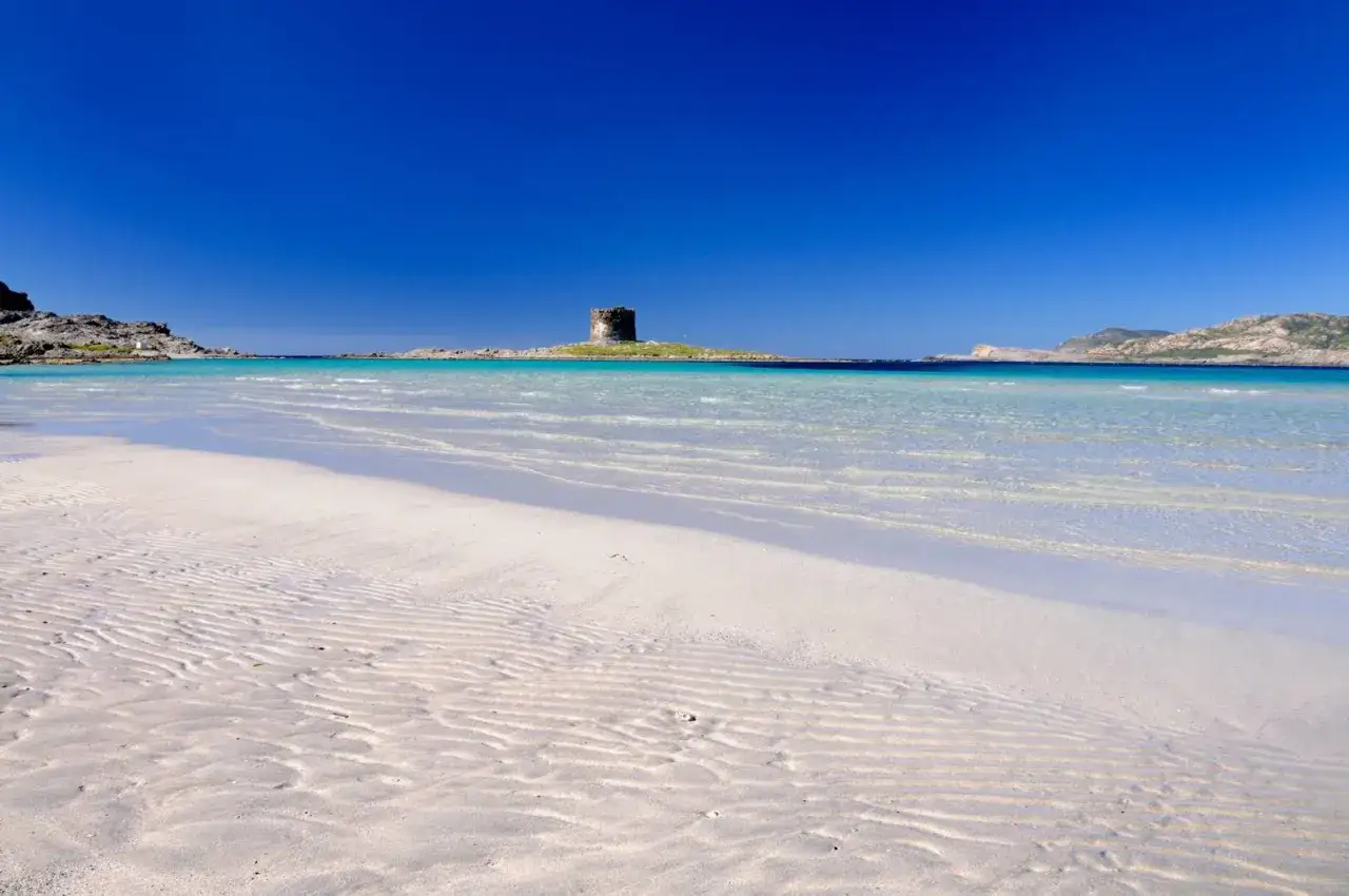 Torre aragonese su isolotto, acque cristalline e sabbia bianca. Un angolo di paradiso nel nord Sardegna, perfetto per una mappa delle spiagge da sogno.