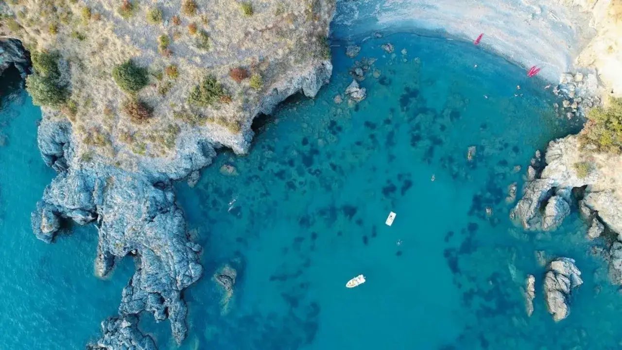 Vista aerea di una baia con acque cristalline, rocce scoscese e una spiaggia di ciottoli. Un vero paradiso, tra le scalea spiagge pi&ugrave; belle.