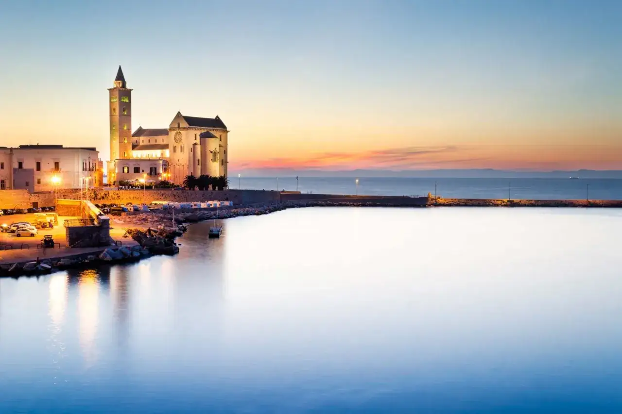 Trani: la cattedrale romanica si specchia nel porto al tramonto. Un luogo incantevole da scoprire, tra vicoli e mare.