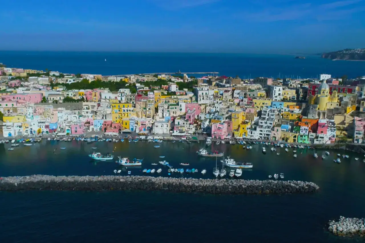 Colorate case a picco sul mare, barche ormeggiate e un cielo azzurro. Ecco cosa vedere a Procida, un gioiello italiano.