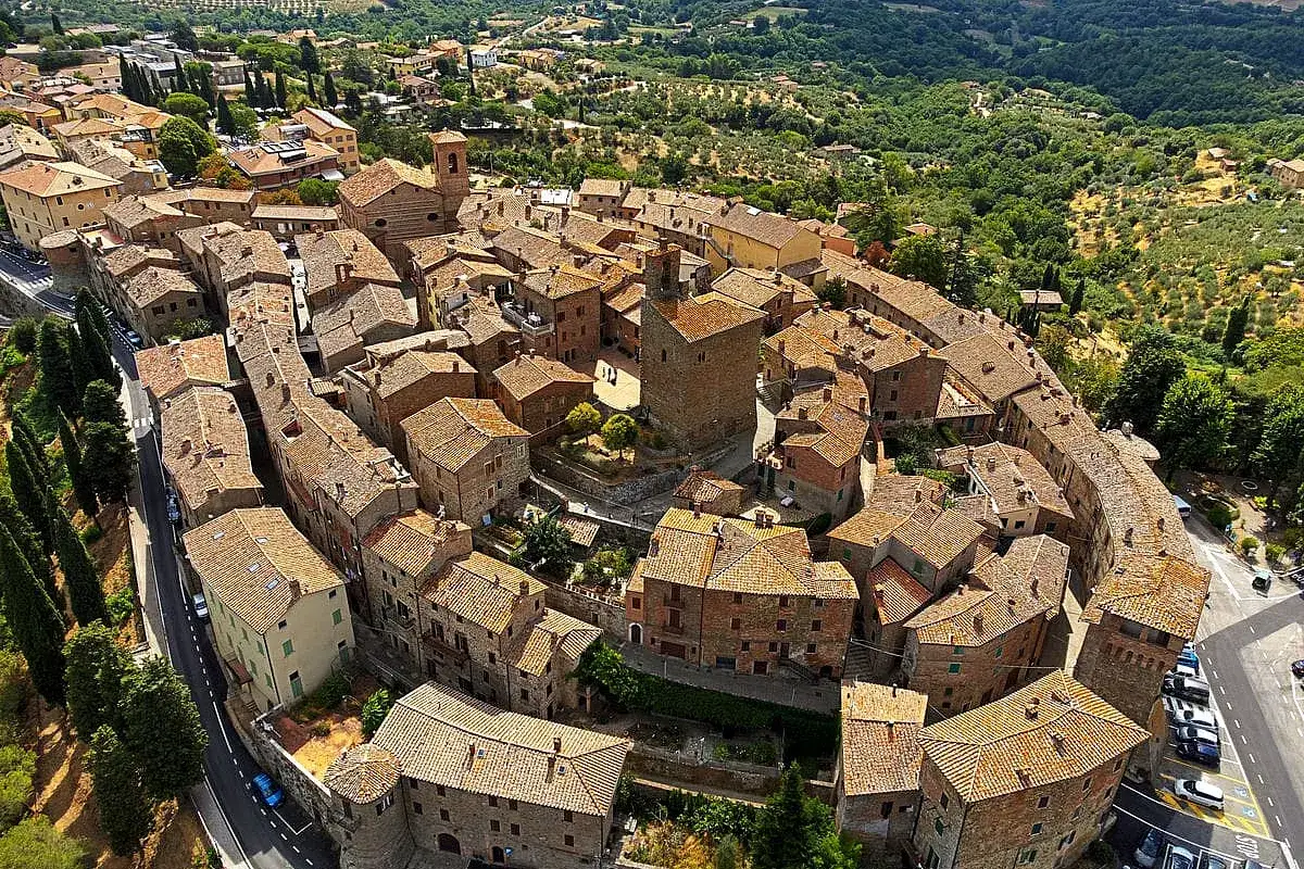 Un borgo medievale in Umbria, con tetti in cotto e un'antica torre, incastonato tra dolci colline verdi. Uno dei borghi più belli dell'Umbria.
