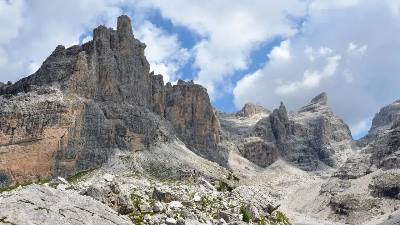 Rifugio alpino incastonato tra imponenti vette rocciose, ideale per gite in Trentino in giornata.