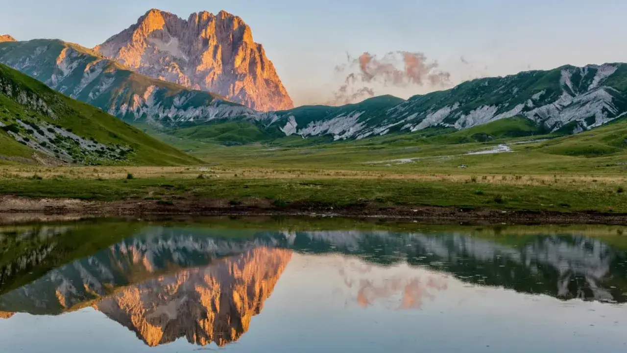 Riflesso dorato del Corno Grande sul lago, un'alba mozzafiato sul cammino del Gran Sasso.