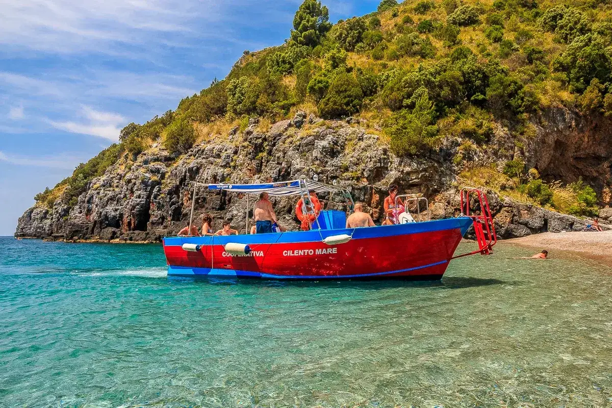 Gita in barca a Marina di Camerota, con gente che si gode il mare cristallino e la costa rocciosa. Un'ottima idea su cosa fare a Marina di Camerota.