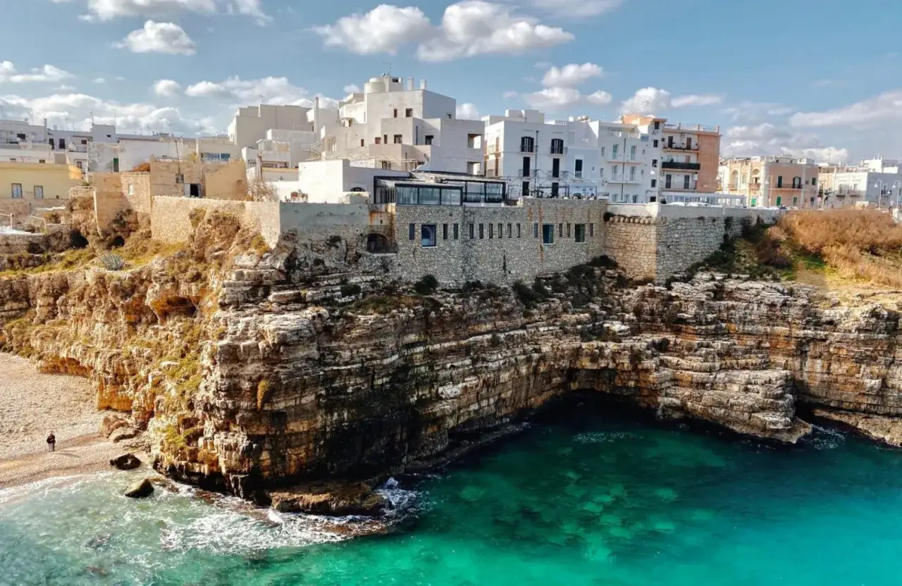 Scogliere mozzafiato e case bianche a picco sul mare turchese, un'immagine iconica dei borghi da visitare in Puglia.