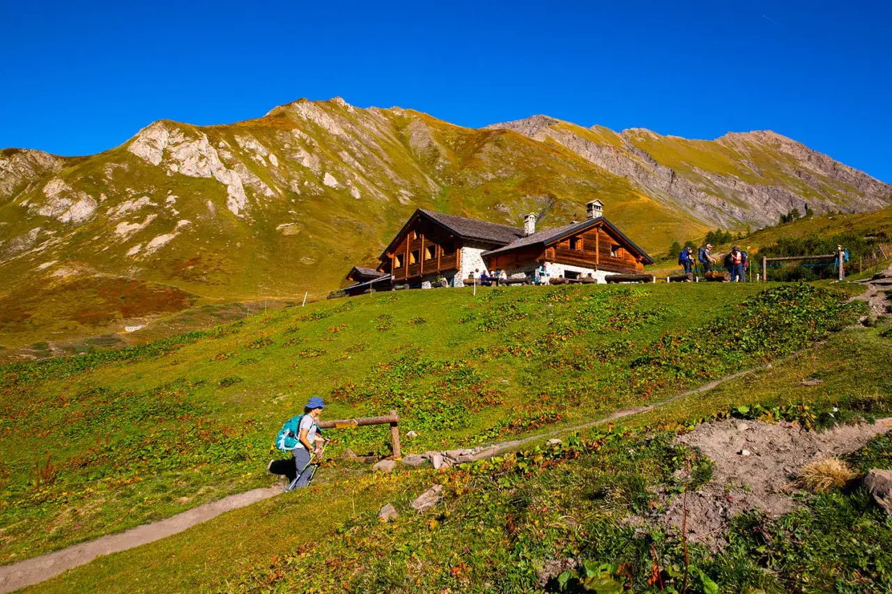 Sentiero verso rifugi valle d'Aosta facili, con escursionista e montagne sullo sfondo.