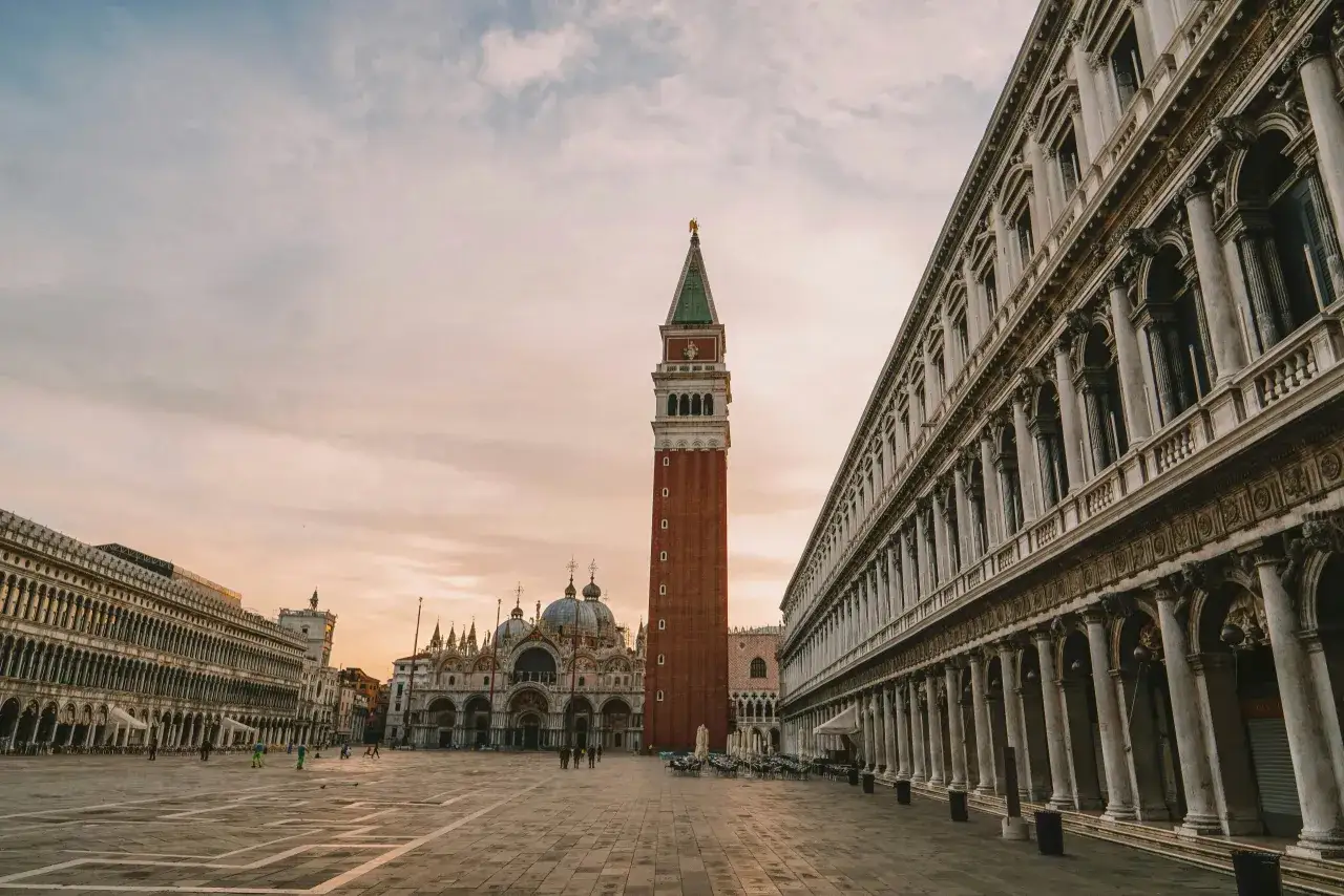 Alba a Piazza San Marco Venezia. La Basilica e il Campanile si stagliano contro il cielo rosato, con le Procuratie a destra.