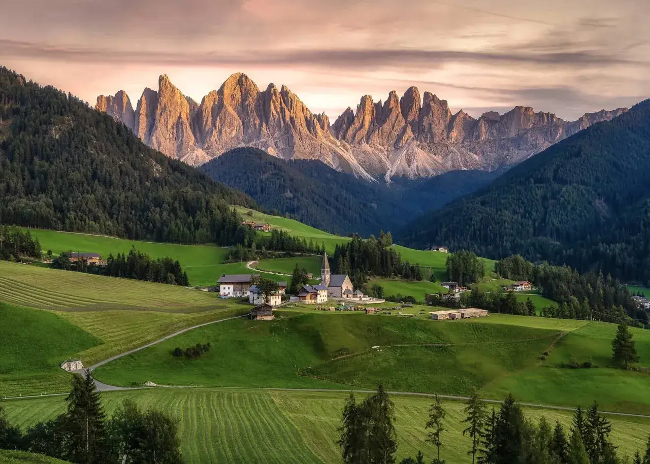 Villaggio alpino con chiesa e montagne imponenti. Un luogo da sogno per scoprire cosa vedere in Trentino Alto Adige.