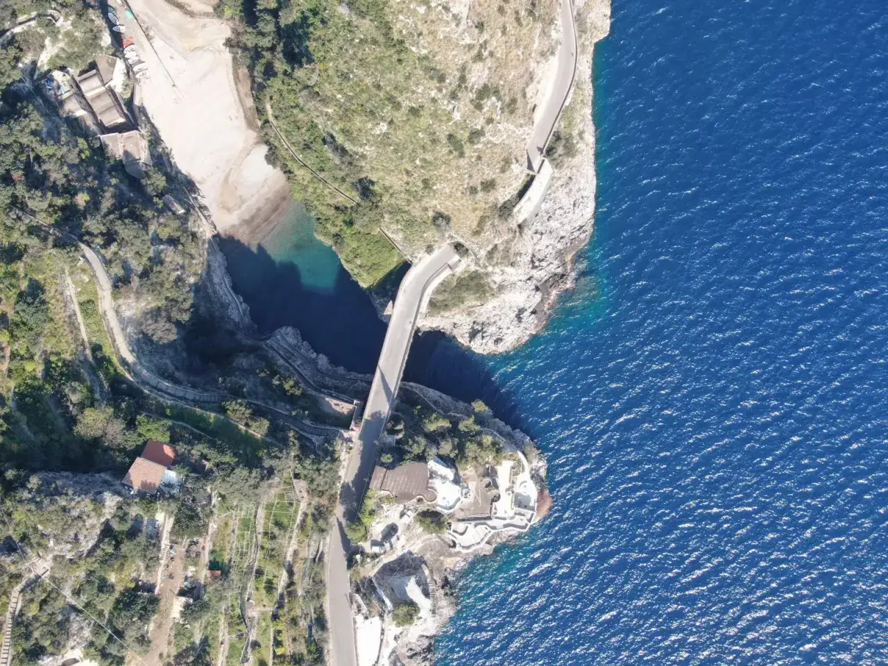 Vista aerea del furore costiera amalfitana, con il ponte che attraversa la baia e il mare blu intenso.