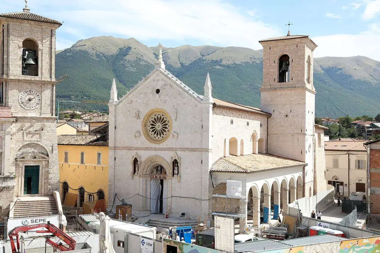 La basilica di Norcia oggi, con le montagne sullo sfondo, mostra i lavori di ricostruzione dopo il terremoto.