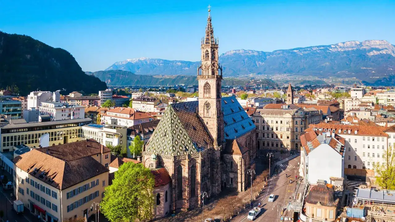 Vista aerea di Bolzano con il Duomo e le montagne. Perfetto per scoprire cosa vedere a Bolzano in un giorno, tra tetti colorati e campanili.