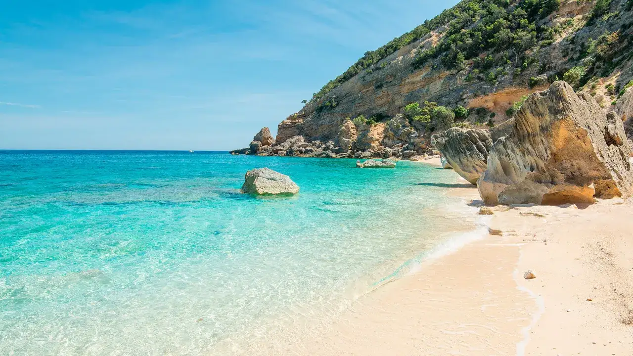 Spiaggia incantevole con acque cristalline e scogliere verdi. Un vero mare bello del nord Italia, perfetto per rilassarsi.