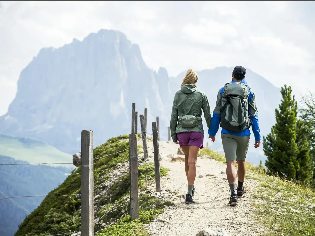 Coppia in escursione, godendosi le loro passeggiate in montagna con zaini e abbigliamento tecnico, sullo sfondo di maestose cime.