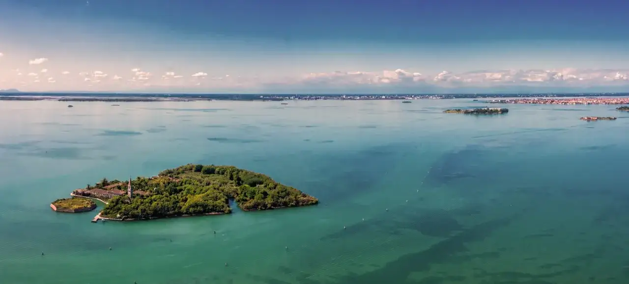 L'isola di Poveglia, con i suoi edifici storici e la vegetazione rigogliosa, si staglia nel mare turchese. Un luogo affascinante, l'isola di Poveglia si pu&ograve; visitare, offrendo scorci unici sulla laguna.