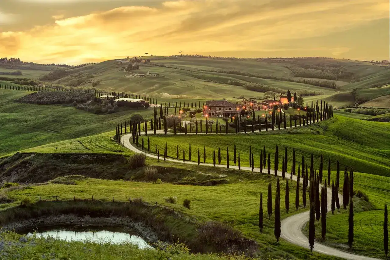 Colline ondulate, cipressi lungo una strada tortuosa e un casale illuminato al tramonto: ecco cosa vedere in Toscana per un'esperienza indimenticabile.