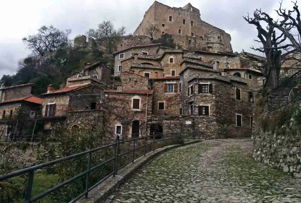 Antico borgo di Castelvecchio di Rocca Barbena con case in pietra e un castello in cima alla collina.