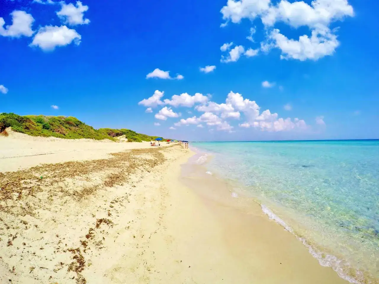 Spiagge Puglia Salento: sabbia dorata, mare cristallino e cielo azzurro con nuvole bianche. Un angolo di paradiso.
