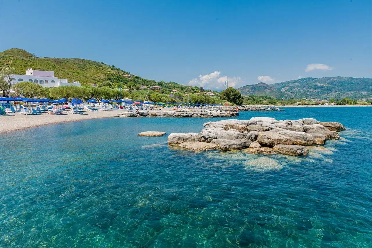 Spiaggia attrezzata con ombrelloni e lettini, mare cristallino e rocce affioranti. Un angolo da sogno tra i posti più belli del Cilento mare.