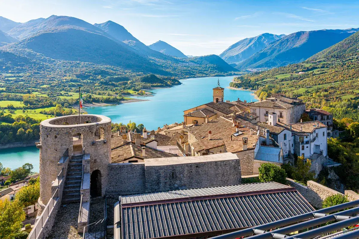 Borgo medievale con torre e lago turchese, un'ottima meta per scoprire cosa vedere in Abruzzo.