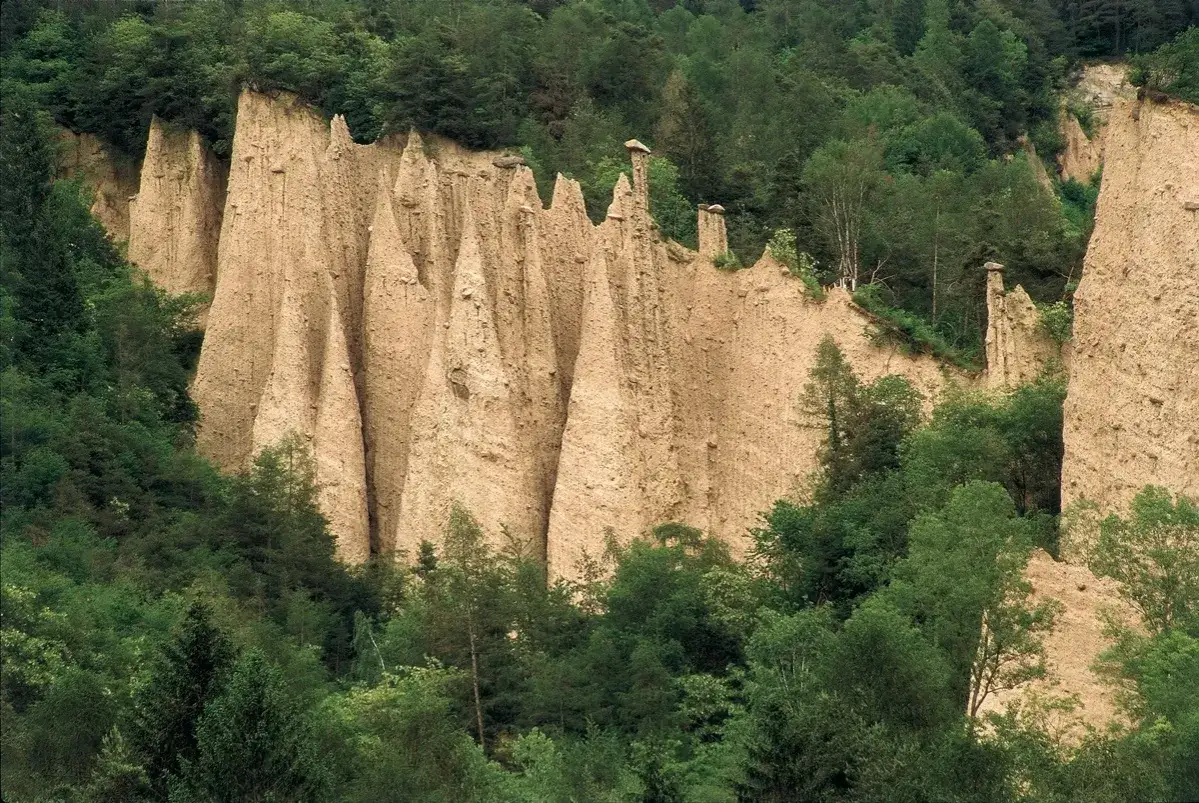 Le piramidi di terra del Val di Cembra, scolpite dal tempo, emergono da un verde lussureggiante.
