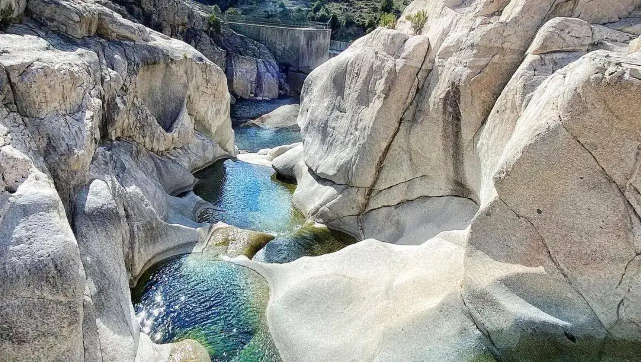 Acque cristalline tra rocce scolpite, perfette per un bagno rinfrescante nelle cascate in Sardegna.