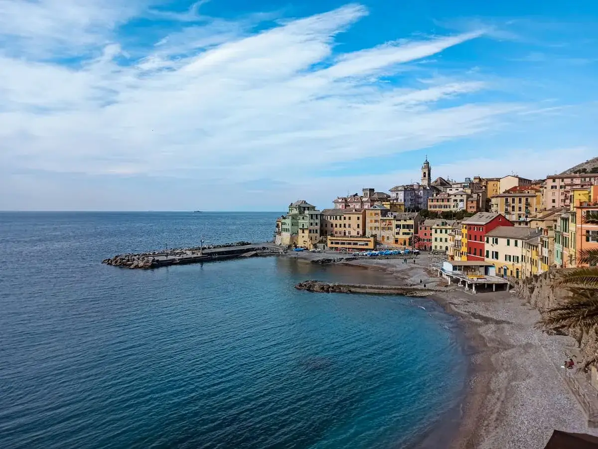 Colorate case liguri si affacciano sul mare blu, con un molo e una spiaggia di ciottoli. Ecco quali sono le colline della Liguria, un incanto.