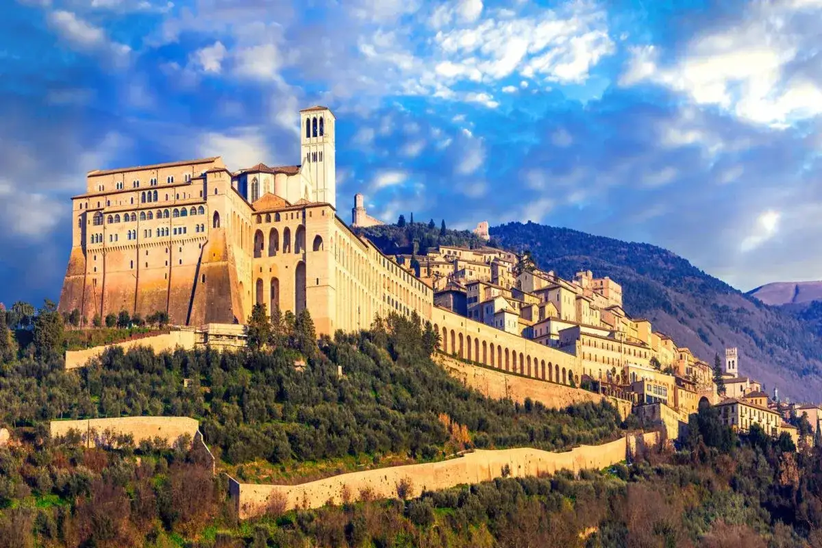 Assisi, un gioiello dell'Umbria, cosa vedere: la maestosa Basilica di San Francesco domina il colle, circondata da antichi borghi e uliveti.