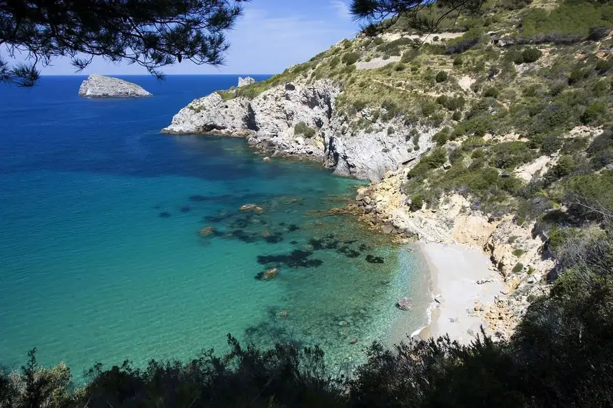 Vista dall'alto della cala del gesso, Monte Argentario, con acque cristalline e scogliere rocciose.