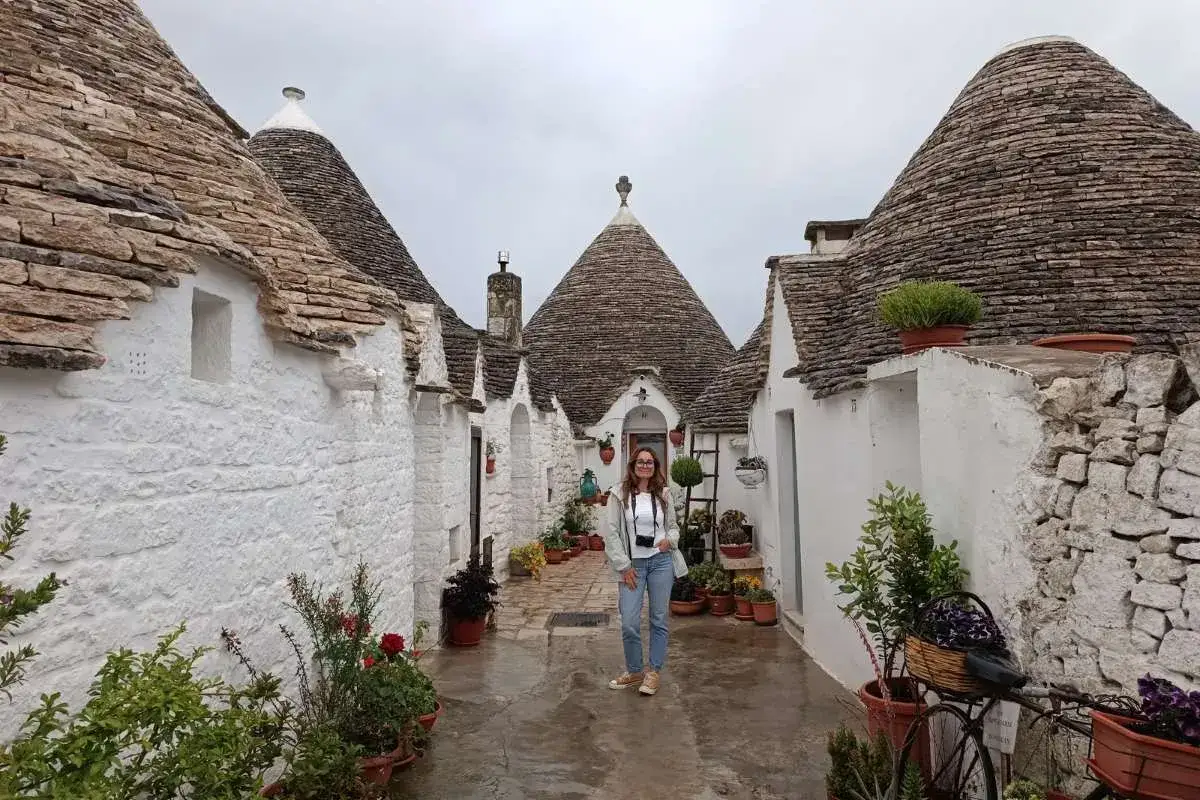 Una donna in un vicolo tra i trulli, un'immagine perfetta per scoprire cosa vedere vicino Alberobello.